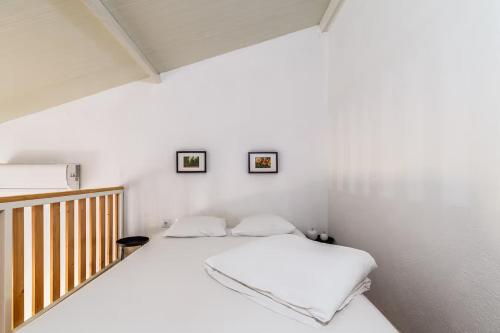 Casa das Pipas Palmela #6 في بينهال نوفو: غرفة نوم بيضاء بسرير وصورتين على الحائط