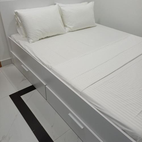 ein weißes Bett mit weißen Laken und Kissen in der Unterkunft Saafu residents in Male City