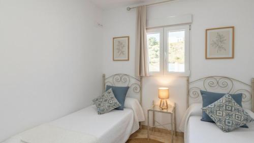 ein Wohnzimmer mit 2 weißen Betten und einem Fenster in der Unterkunft Villa Diego Torrox by Ruralidays in Torrox