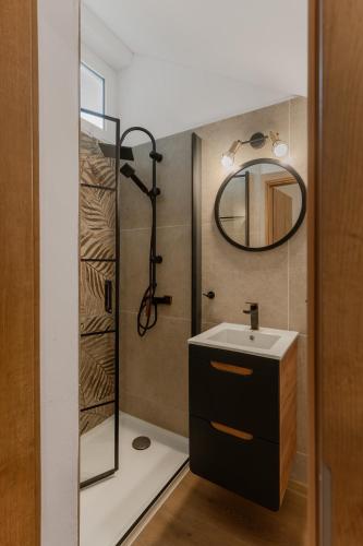 a bathroom with a shower with a sink and a mirror at Apartamenty U Dragana in Kaštela