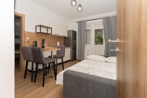 a bedroom with a bed and a table and a kitchen at Apartamenty U Dragana in Kaštela