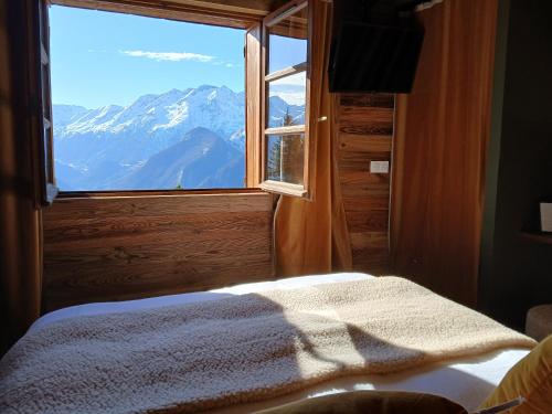 a bedroom with a window with a view of a mountain at Demeure Sauvage - Étage 1 in Villard-Reculas