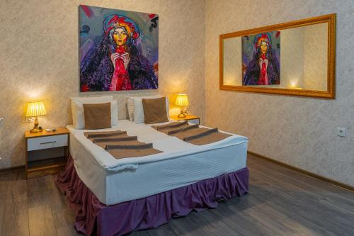 a bedroom with a large bed with a painting on the wall at Salam Baku Hotel (SBH) in Baku