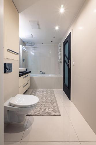 a white bathroom with a toilet and a bath tub at Apartament Avignon in Wrocław