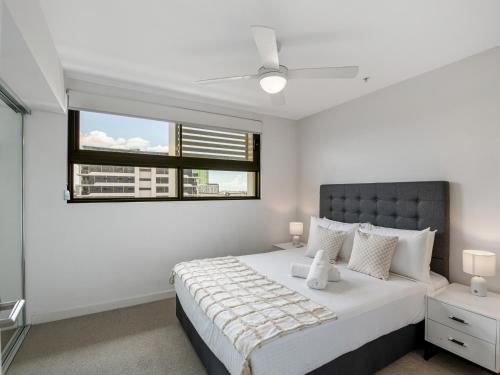 a white bedroom with a large bed and a window at Timi Property in Brisbane