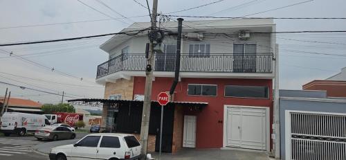 un edificio rosso con una macchina bianca parcheggiata di fronte di Apartamento 2 quartos c/ ar-condicionado e garagem a Indaiatuba