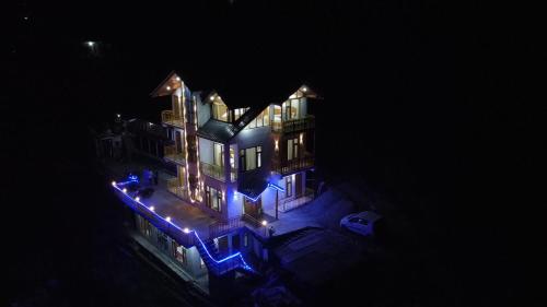 a large house with blue lights on it at night at woodstock villa & cafe in Jibhi