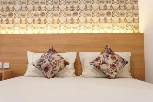 a bed with two pillows and a wooden headboard at Senayan Suites in Jakarta