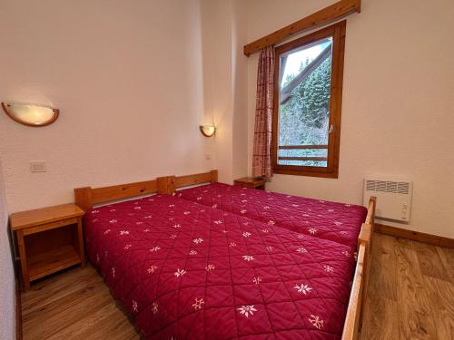 een slaapkamer met een bed met een rood dekbed en een raam bij Résidence Saboia B54 Clés Blanches Courchevel in La Tania