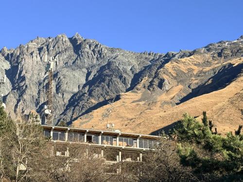 a house on a hill with mountains in the background at ADRESATI Stepantsminda in Stepantsminda