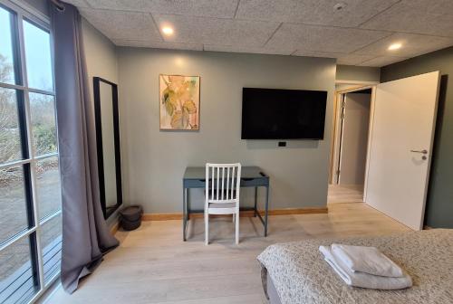 1 dormitorio con mesa y TV en la pared en Odense Garden Apartment, en Odense