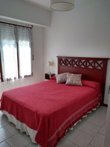 a bedroom with a large bed with a red bedspread at Dpto céntrico cómodo in Miramar