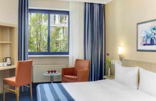 a hotel room with a bed and chairs and a window at Hotel Nürnberg City Center by Leonardo Hotels in Nürnberg