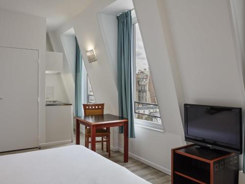 a bedroom with a bed and a desk and a television at Aparthotel Adagio Access Paris Philippe Auguste in Paris