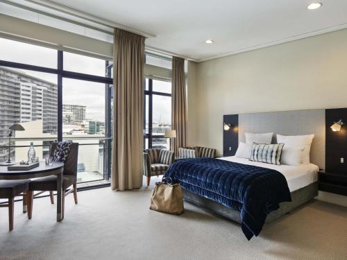 Una habitación de hotel con una cama, una mesa y sillas. en The Sebel Auckland Viaduct Harbour, en Auckland