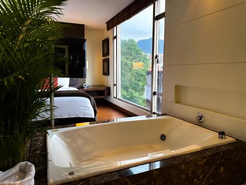 a large white bath tub in a room with a bedroom at Hotel Cabrera Imperial By key 33 in Bogotá