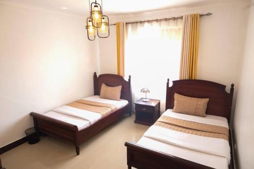 Green Valley Palace A quiet Happy Place to stay في Namulanda: غرفة نوم بها سريرين ونافذة