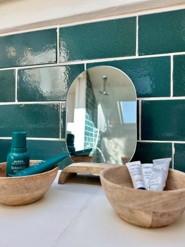 un mostrador de baño con dos cuencos de madera y un espejo en La Mer, en De Panne