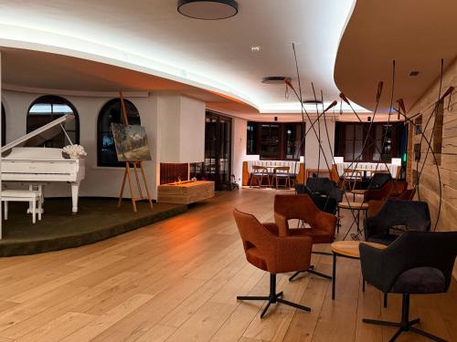 a living room with a white piano and chairs at Tieflehner Hof Pitztalhaus Hotel in Sankt Leonhard im Pitztal