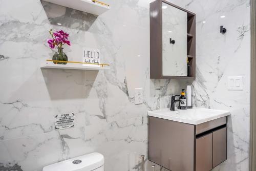 a white bathroom with a sink and a toilet at Velvet Vue Suite Near JFK, UBS Arena, & 30mins from City in Bellerose Terrace