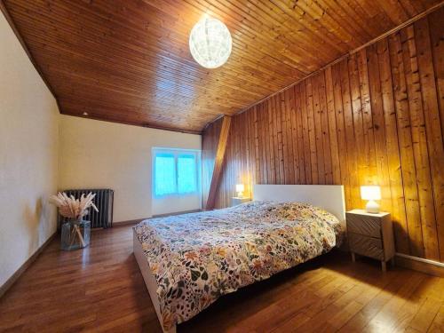 a bedroom with a bed and a wooden wall at La maison d'à côté in Pluherlin