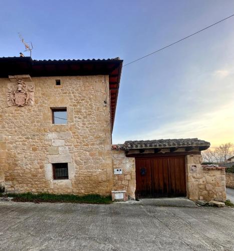 a large brick building with a wooden door at CASA RURAL PALACIO LOS LABREQUINES in Villacomparada de Rueda