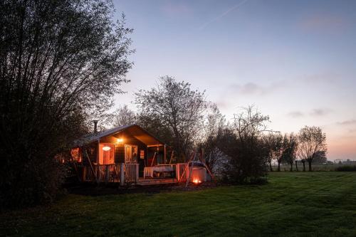 a tiny house in a field at sunset at Smûk Thuskes vlakbij het water in Friesland natuur, ontspanning,houtkachel in Echtenerbrug