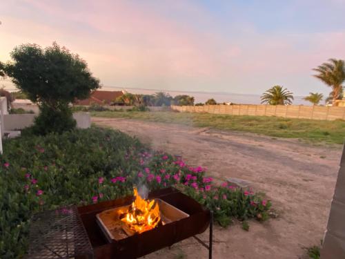 a fire pit on the side of a road with flowers at Starboard Self Catering - St Helena Bay in Stompneusbaai
