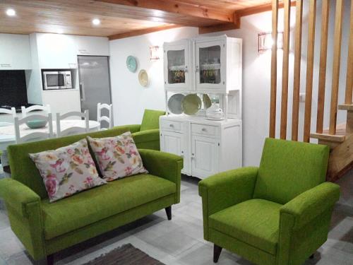 a living room with two green chairs and a table at Casa do Terreiro in Pardieiros