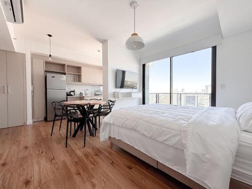 a white bedroom with a bed and a table and chairs at Dpto con piscina a pasos del Shopping del Sol in Asuncion