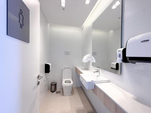 a white bathroom with a toilet and a sink at Dpto con piscina a pasos del Shopping del Sol in Asuncion