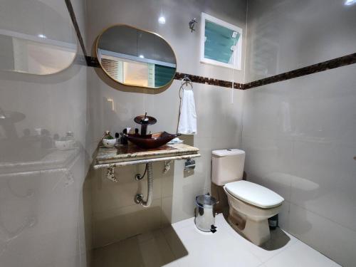 ein Badezimmer mit Toilette, Waschbecken und Spiegel in der Unterkunft Casa Praia Alegre in Penha