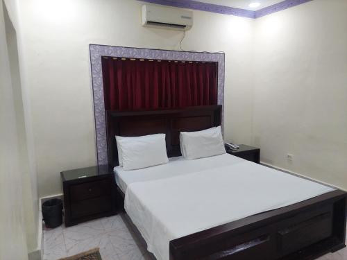 a bedroom with a large bed with a red curtain at Hotel Royal Vista in Karachi