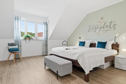 een witte slaapkamer met een groot bed en een stoel bij Bernsteinquartier BQ 6e in Kolpinsee