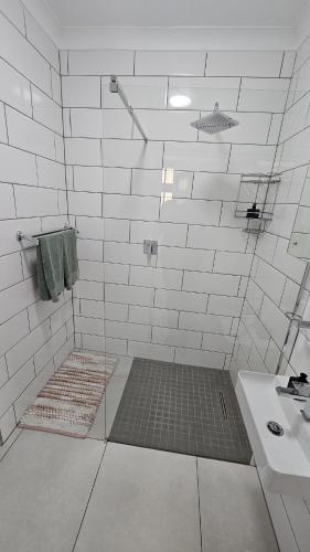 a white tiled bathroom with a sink and a shower at Protea Rus in Wellington