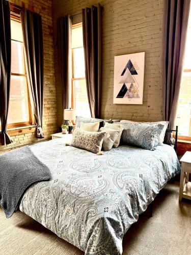 a large bed in a bedroom with windows at Loft on Lake Ave in Duluth