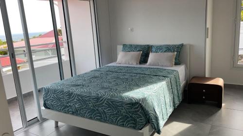 a bedroom with a bed with a green comforter at Villa Outaouais T4 in Bielle