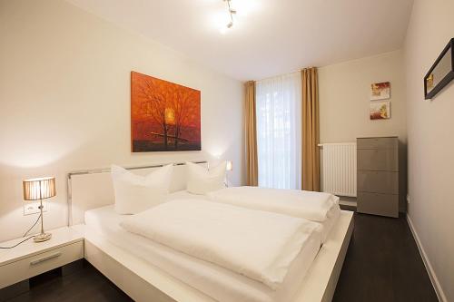 a white bedroom with a large white bed and a window at Residenz am Balmer See - BS 05 mit Wellnessbereich in Balm
