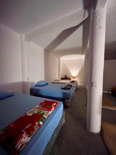 a room with three beds and a pole at Mandalas Hideout in San Pedro La Laguna