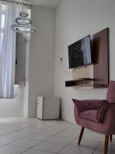 a living room with a couch and a tv on a wall at FA Hotel Andrade in Florianópolis