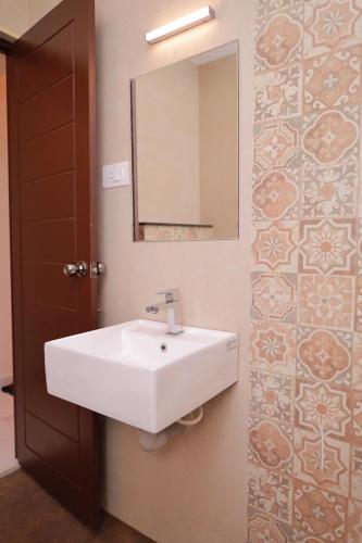 a bathroom with a white sink and a mirror at Hotel Sahaya Arasi in Kanyakumari