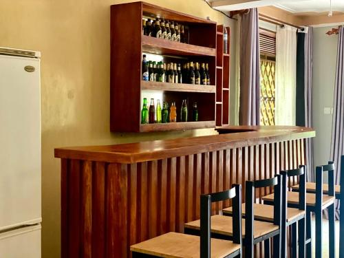 Un bar con sillas y botellas de alcohol. en Nilevic Guest House Entebbe, en Entebbe
