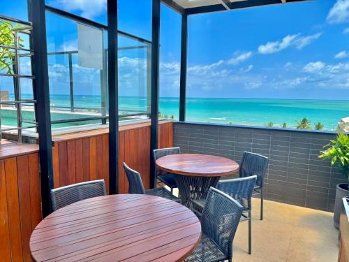two tables and chairs on a balcony with the ocean at UMI Flats - Intermares by Refúgio Hospedagens in Cabedelo