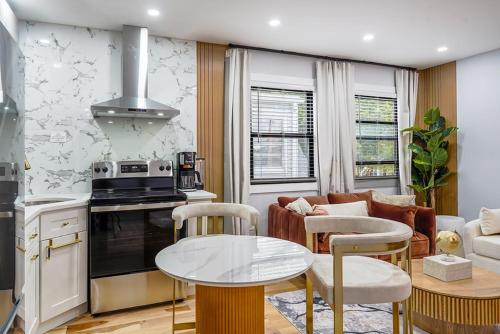 a kitchen and living room with a table and a couch at Velvet Vue Suite Near JFK, UBS Arena, & 30mins from City in Bellerose Terrace