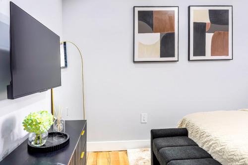 a bedroom with a bed and a tv on a wall at Velvet Vue Suite Near JFK, UBS Arena, & 30mins from City in Bellerose Terrace