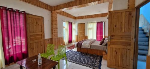 a bedroom with a bed and a table and some windows at woodstock villa & cafe in Jibhi