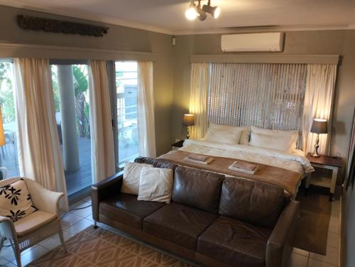 a bedroom with a large bed and a couch at 78on5th in Hermanus in Hermanus