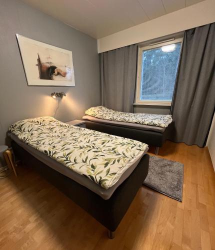 two beds in a room with a window at Cityflat by Travel Center in Lappeenranta