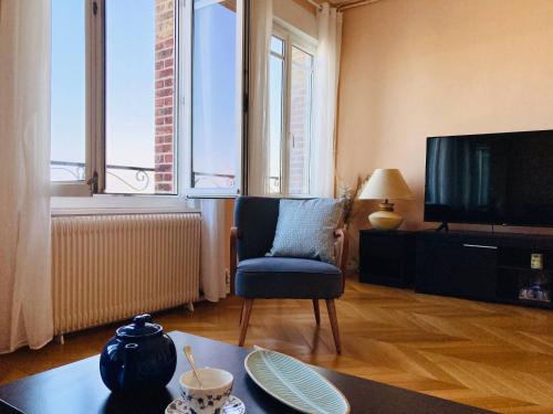 een woonkamer met een tv, een stoel en een tafel bij Les Pieds dans l'eau appartement vue mer in Dieppe