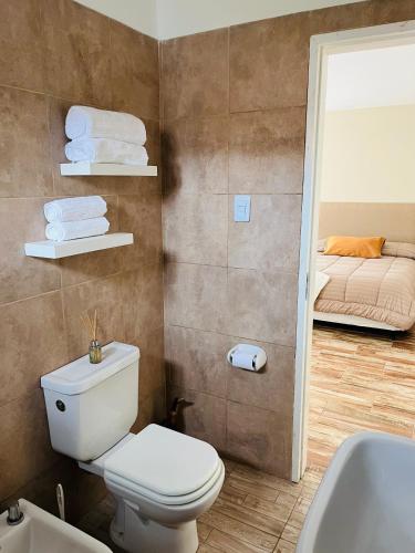 a bathroom with a toilet and a sink and a bed at Corazón de Ayrampos APART in Villa Dolores